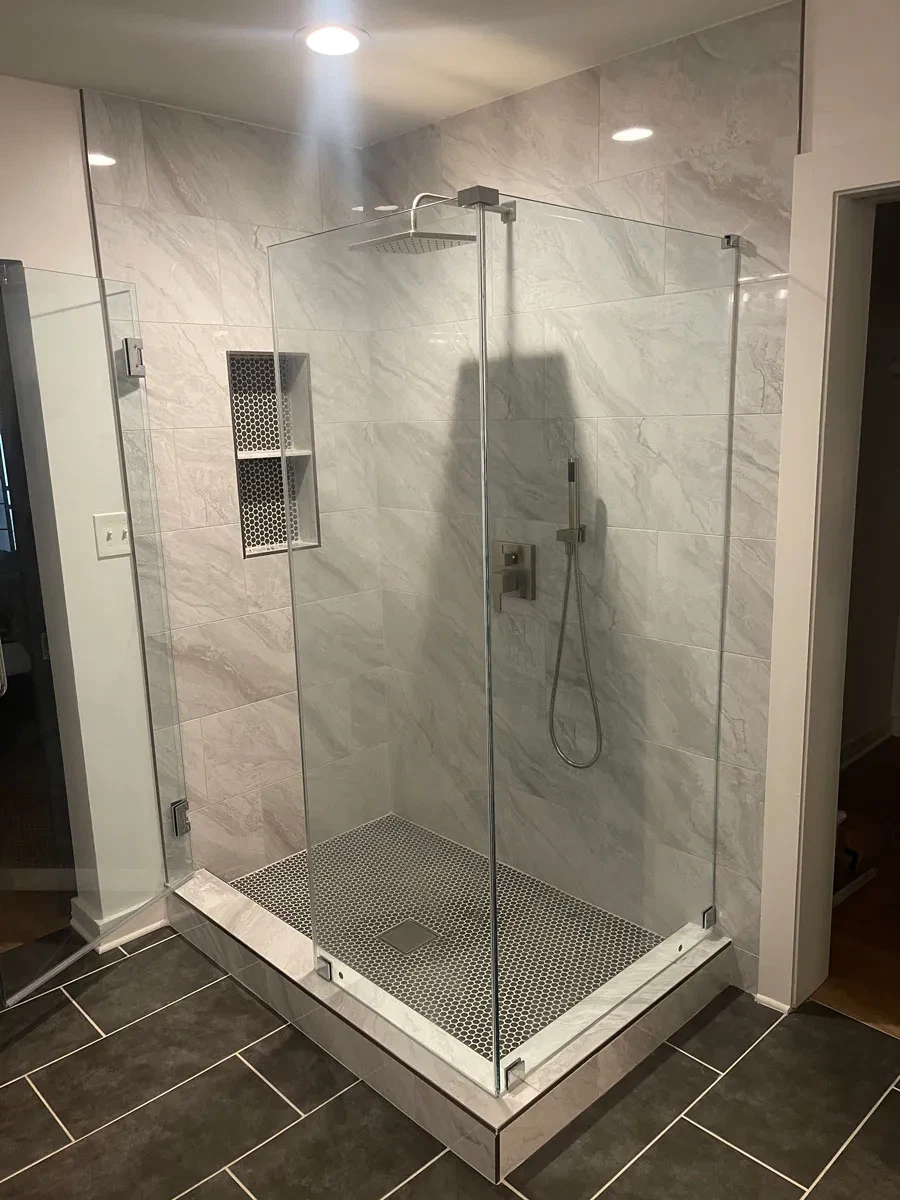 Modern marble tiled walk-in shower with glass doors